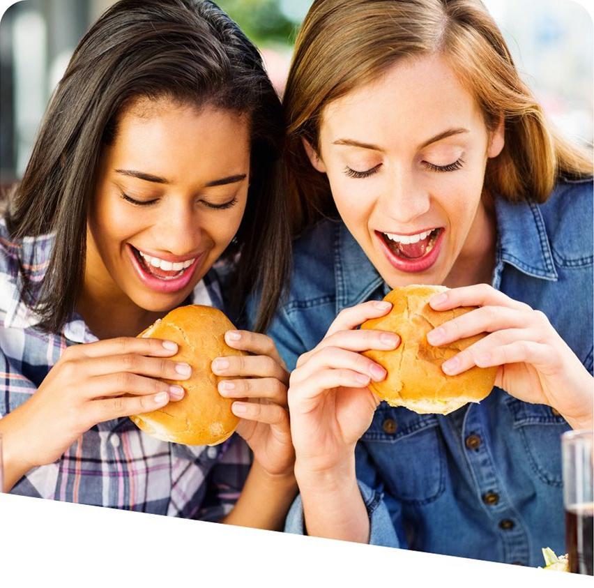 Two young women enjoying sandwiches made with freshly baked bread.